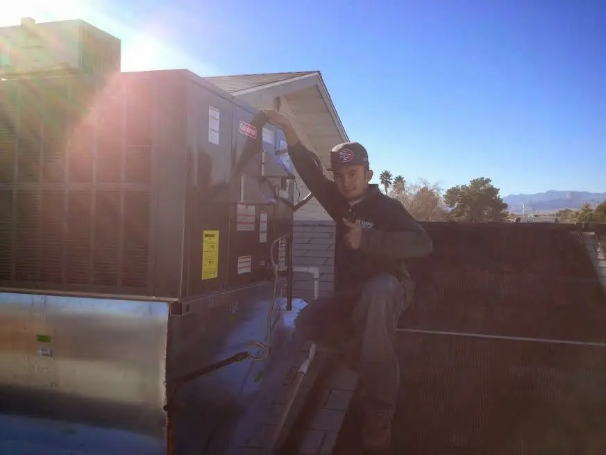 HVAC technician performing Air Duct Cleaning on a rooftop unit in East Aurora